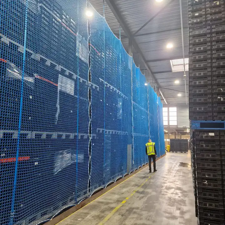 Blauwe scheidingsnetten langs hoge stellingen in een distributiecentrum