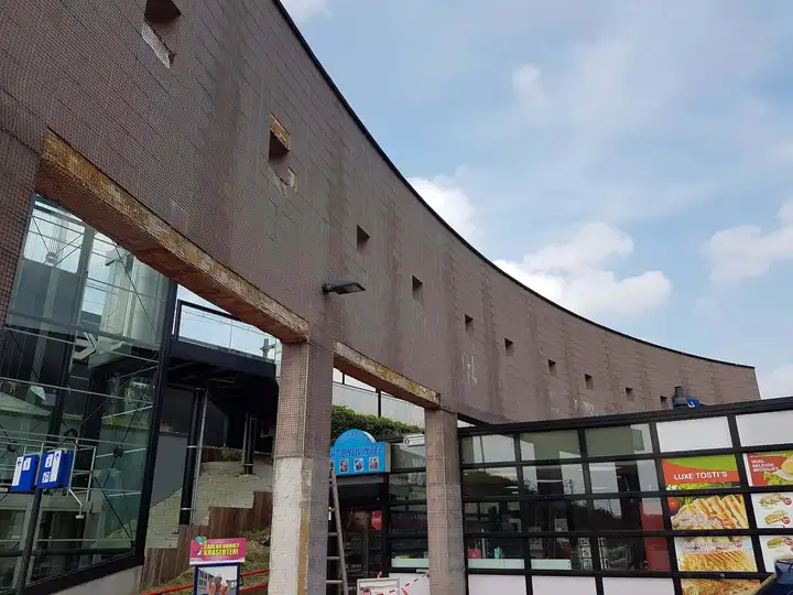 Onopvallend steenslagnet langs een gebogen gevel boven de openbare ruimte