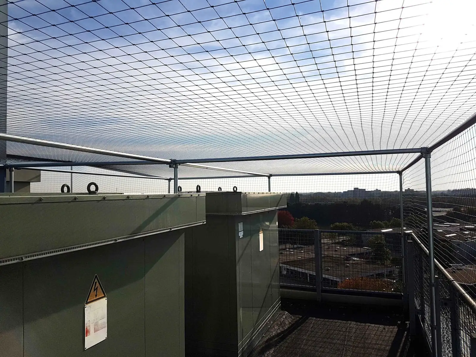 Vogelwering met buizenframe boven technische installaties op een dak